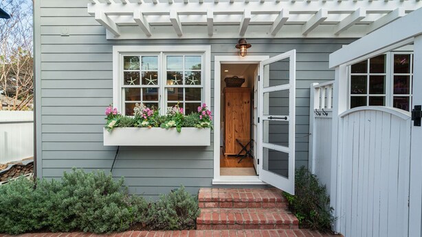 A house with a white front door, a window with a white frame, and a wooden door leading to a garage. - Hagan's Hideaway (Encinitas)