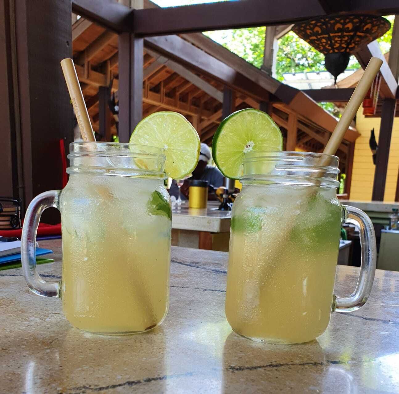 Two mason jars with lime slices and straws on a table.