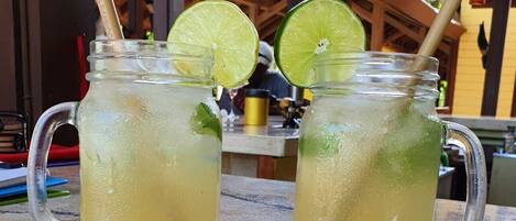 Two mason jars with lime slices and straws on a table.