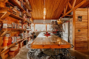 Un interior de madera con una isla central, estanterías y una zona de cocina.