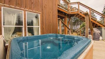 Une cabane en bois avec un jacuzzi, un escalier et une fenêtre avec des rideaux.