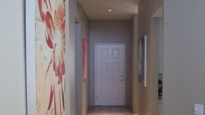 A hallway with a white sculpture on a table, a door at the end, and a painting on the wall. - Charming and Contemporary 5 Star PGA West Condo Stadium on11th Tee Box Lic100888 (La Quinta)