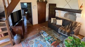Un espacio habitable amplio con techo alto, una escalera de madera, un sofá, una mesa de centro y una alfombra estampada.
