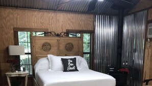 Un lit en bois avec une tête de lit, une table de chevet avec une lampe et un tapis orné de motifs en forme d’étoiles.
