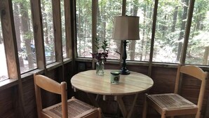 Une table ronde en bois, accompagnée de deux chaises, d’une lampe et d’un vase rempli de fleurs.