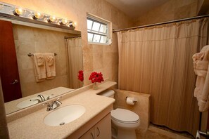 A bathroom with two sinks, a toilet, a shower curtain, and a window.