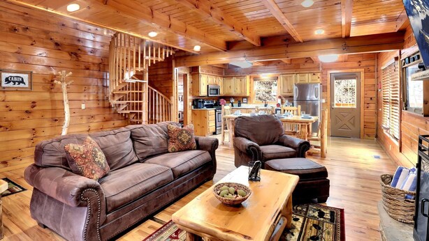 L’intérieur d’une cabine est aménagé avec du bois, il comprend un canapé, un fauteuil, une table et un coin cuisine.