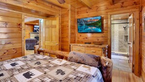 L’intérieur d’un chalet en bois comprend un lit, un téléviseur, une salle de bain avec douche et un coin repas.