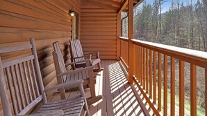 Une terrasse en bois, dotée de bancs et d’une rambarde, qui offre une vue sur une forêt.