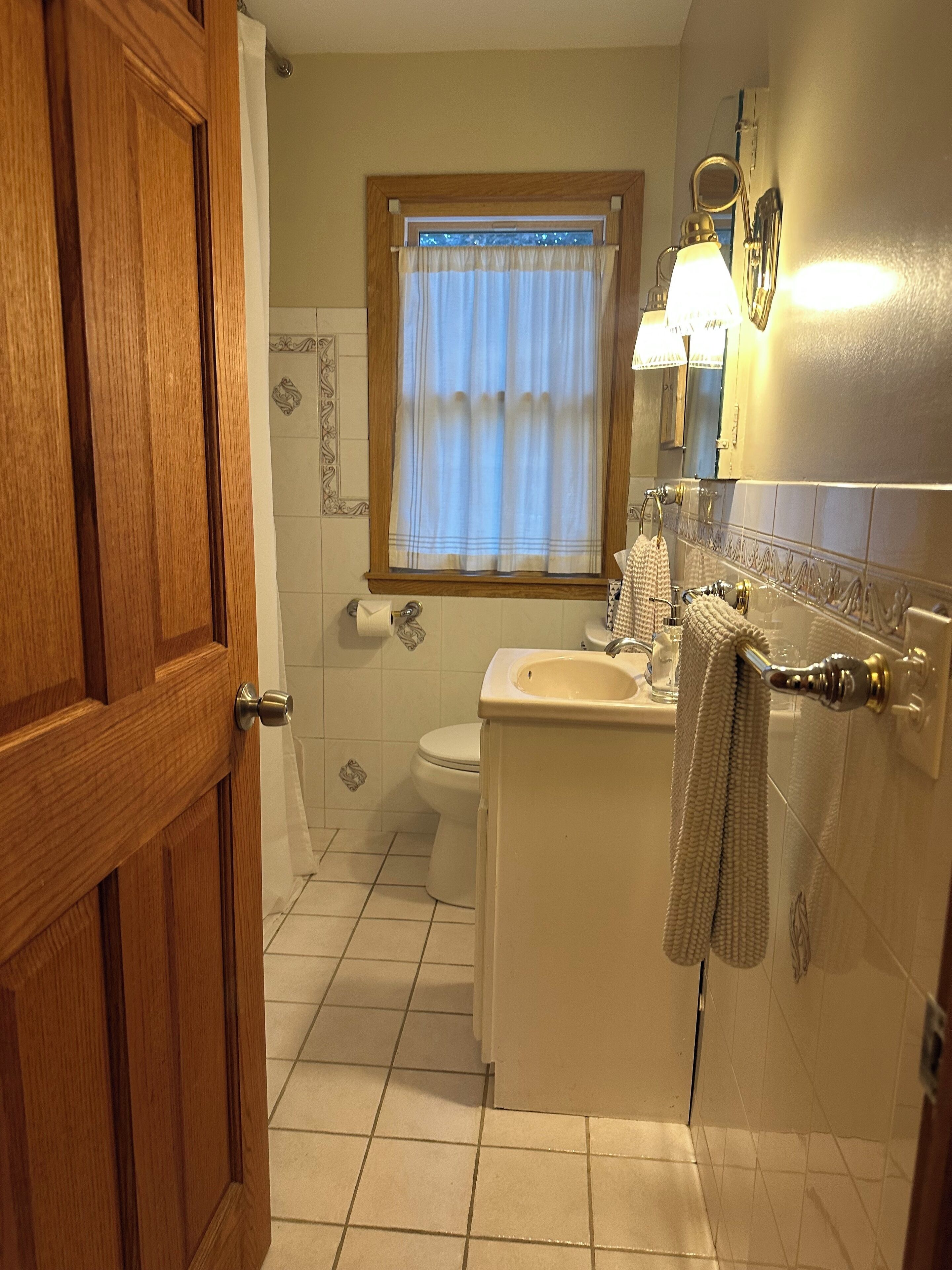Ein Badezimmer mit Toilette, Waschbecken und einem Fenster mit Vorhängen.