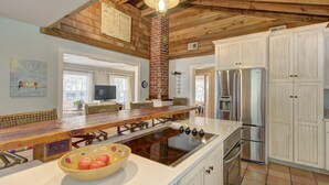 A spacious kitchen with a large island, stainless steel appliances, and a rustic wooden ceiling.