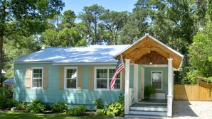 A small, single-story house with a porch and a flag.