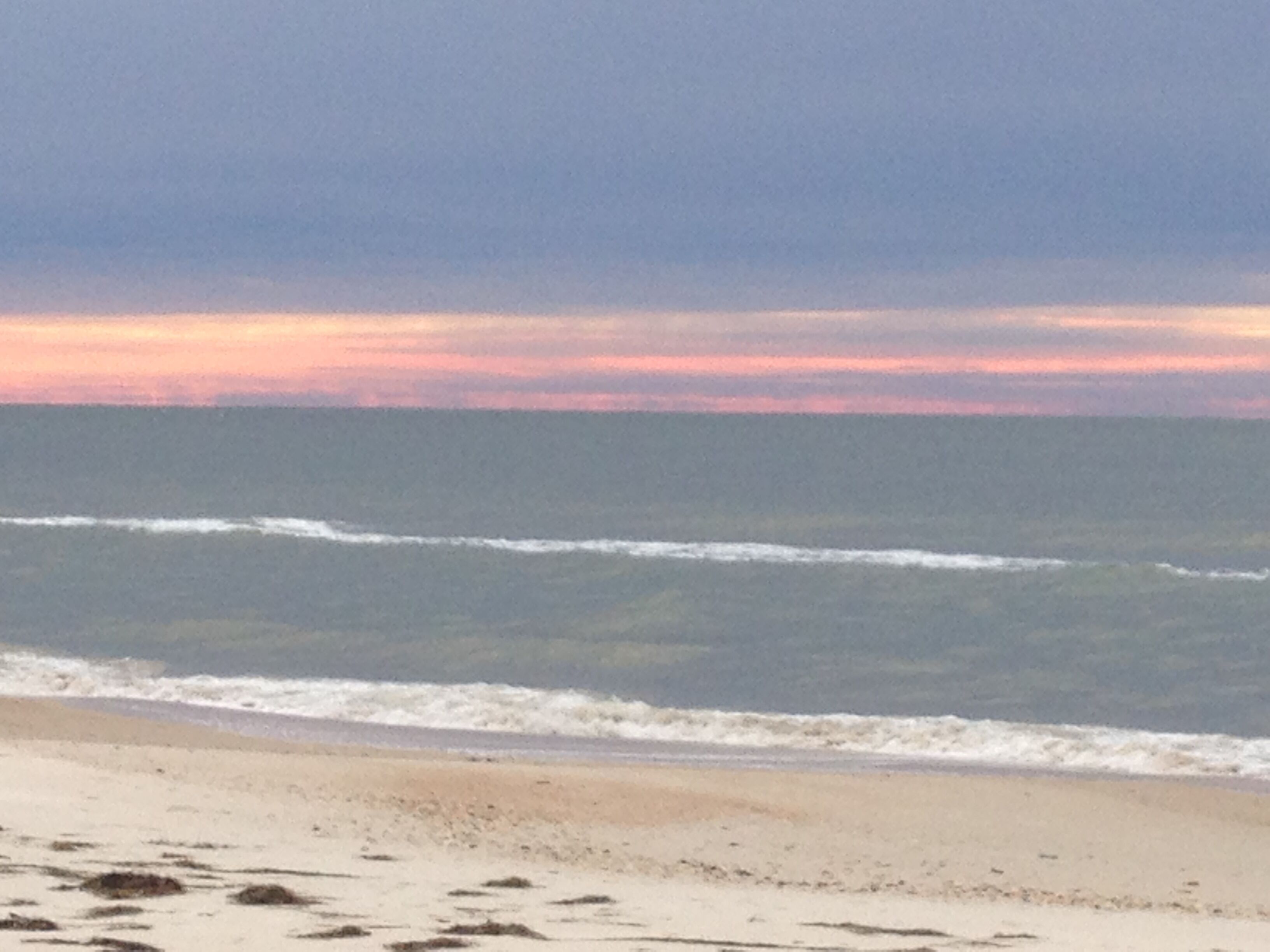Una playa con olas y un atardecer.