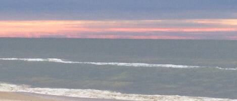 Una playa con olas y un atardecer.