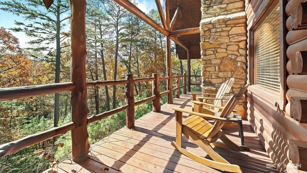 A wooden deck with a stone wall and a wooden railing.