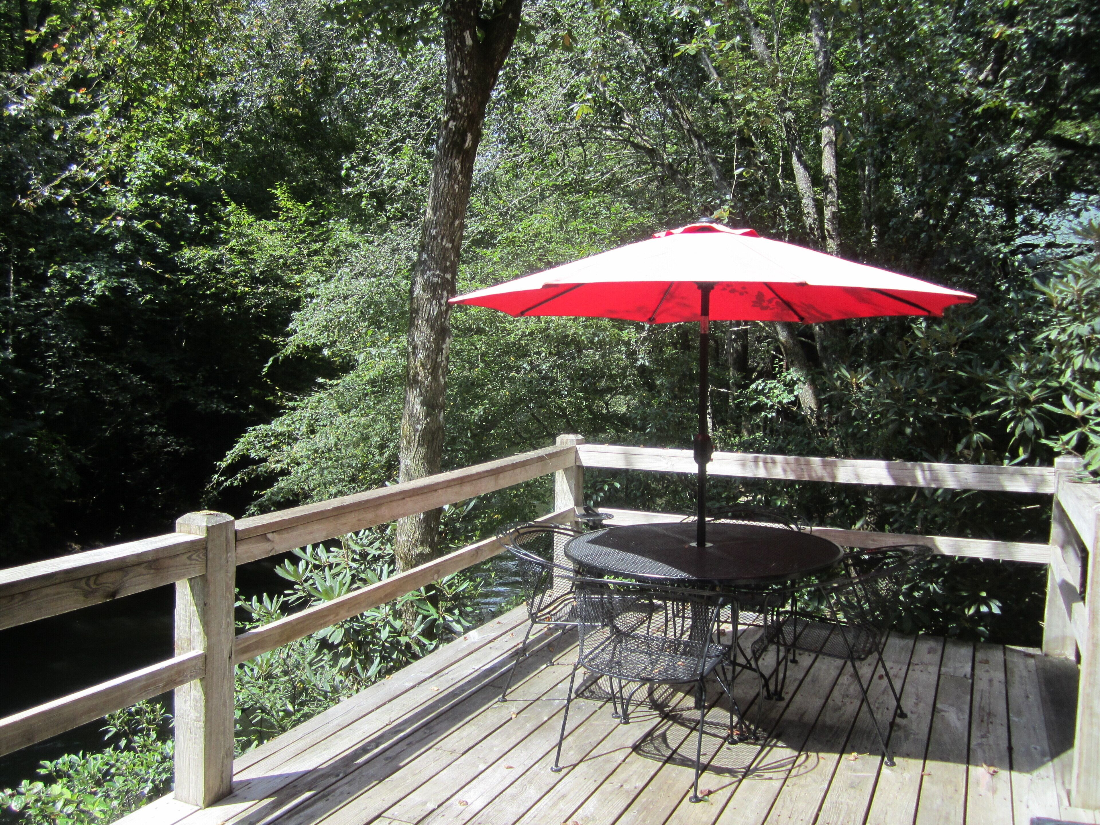 A wooden deck with a table and chairs, an umbrella, and a railing.