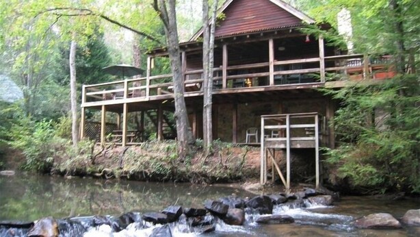 A rustic cabin with a wooden deck and a small waterfall in front. - Waterfront Cabin on Trout Stream W/ Hot Tub, & Internet (BLUE RIDGE)