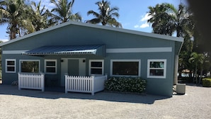 A single-story building with a porch, white picket fence, and a gravel driveway.