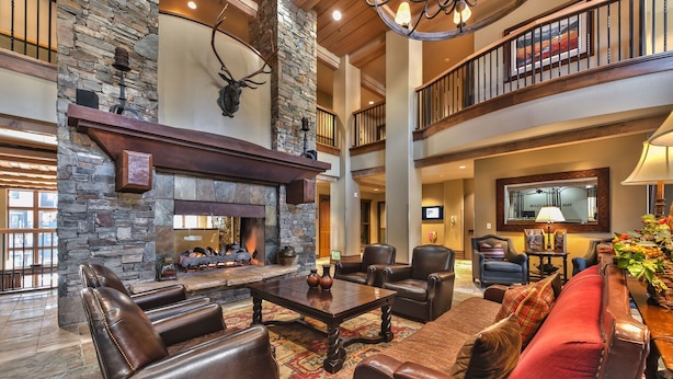 A spacious living area with a stone fireplace, leather furniture, and a high ceiling with wooden beams. - Large Ski In Ski Out 3 Bedroom+Loft Sleeps 10 Pool Hot Tub Vaulted Ceilings MC10 B (Park City)