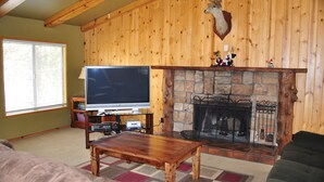 Una sala de estar acogedora con chimenea de piedra, un televisor y una mesa de centro de madera.