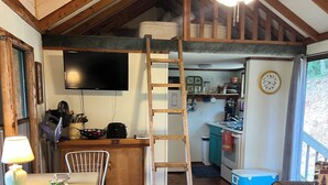 Un intérieur rustique comprenant un coin repas, une échelle, un ventilateur de plafond et une cuisine.