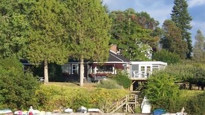 Une propriété au bord du lac, comprenant une maison, un espace extérieur aménagé et un quai.