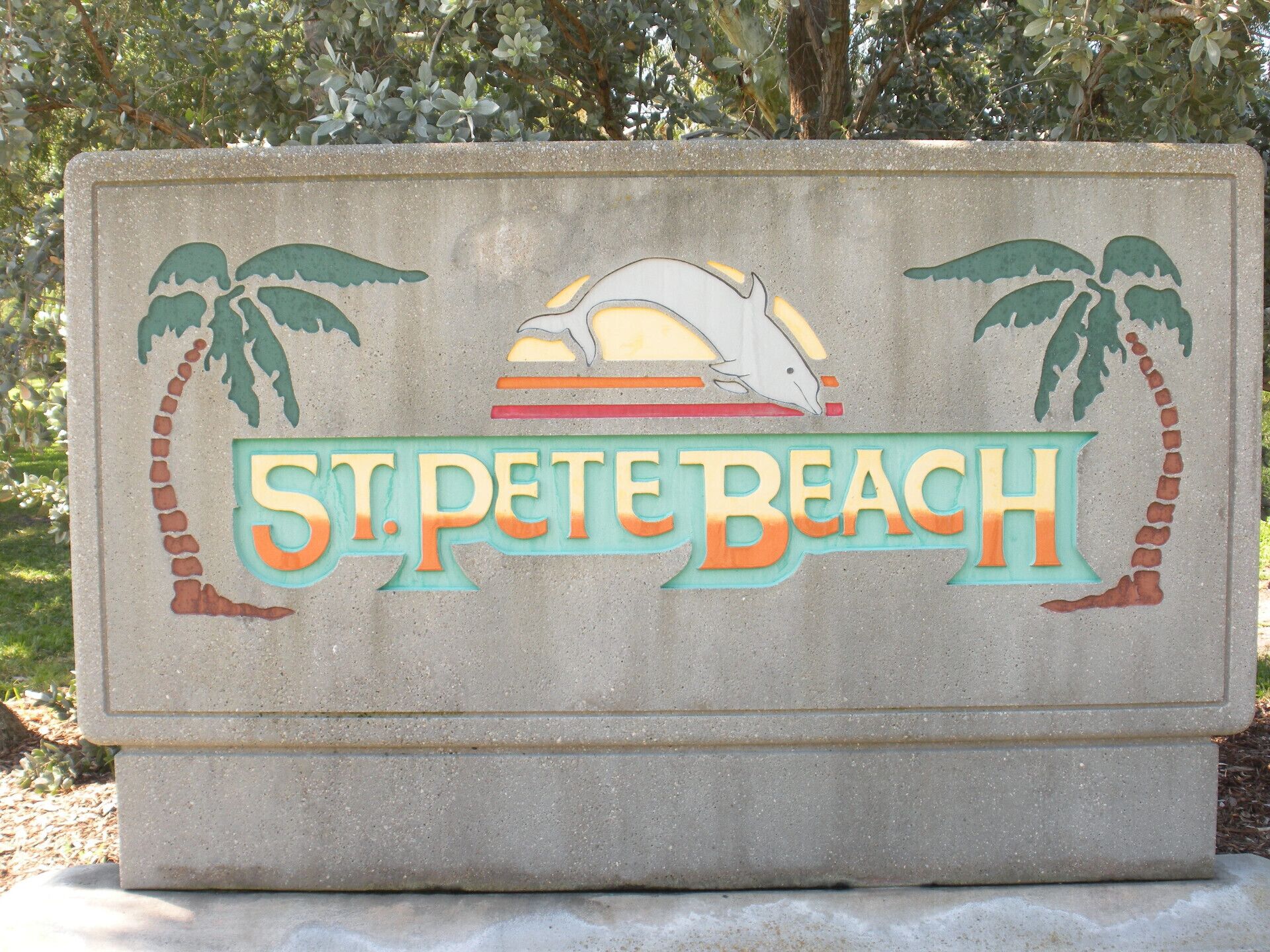 A sign for St. Pete Beach with palm trees and a dolphin graphic.