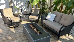 A deck with a fire pit, two sofas, and chairs.