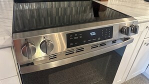 A stainless steel oven with a digital display, knobs, and a vented front.
