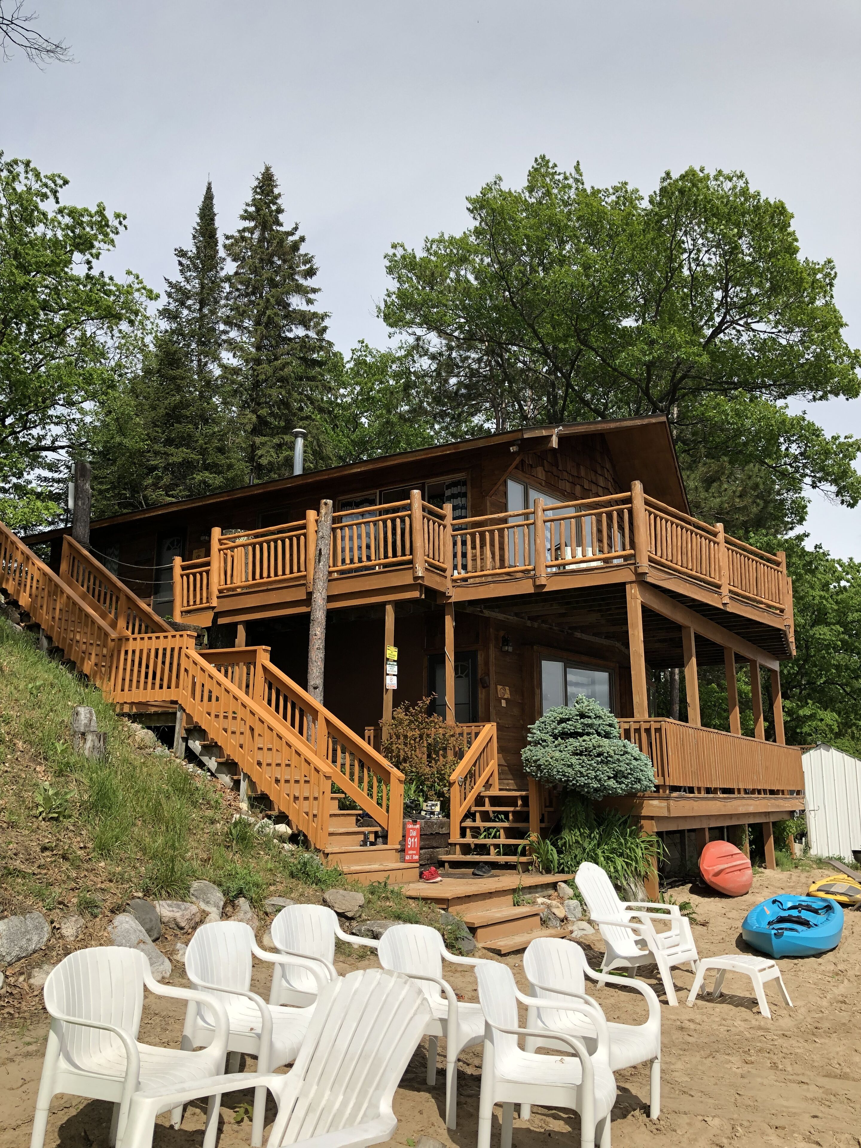 A wooden cabin with a balcony, a staircase, and outdoor seating.