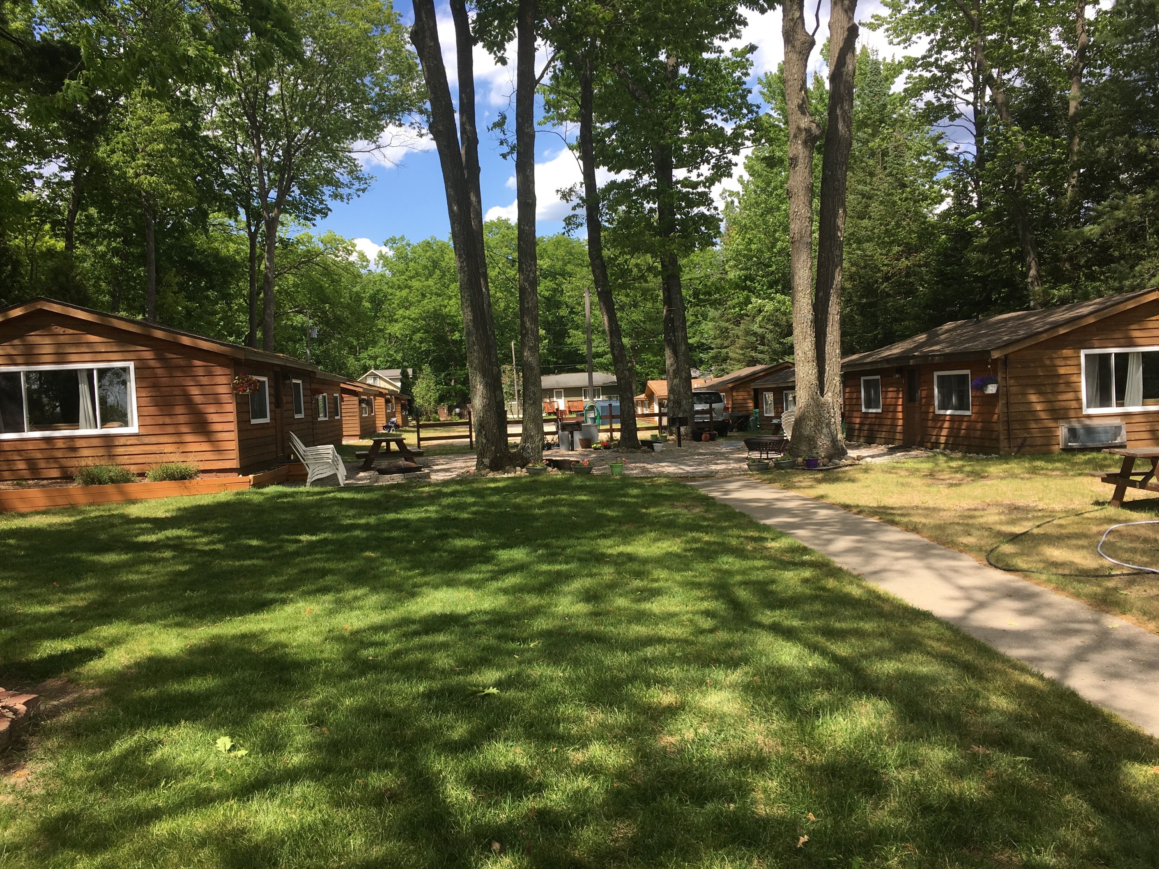 Een camping met meerdere houten hutten, picknicktafels en een heldere lucht.