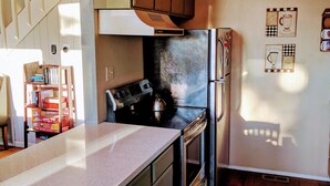 A kitchen with wooden cabinets, a stainless steel refrigerator, and a stove. There is a countertop with a coffee machine and a kettle. - [Skislope Cabin] Hot Tub - Dog Friendly (Truckee)