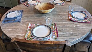 A round wooden dining table set with four plates, two bowls, and various cutlery. - [Skislope Cabin] Hot Tub - Dog Friendly (Truckee)