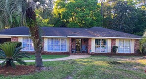 A single-story brick house with a front porch, large windows, and a well-maintained lawn. - Jekyll Beach - Terrapin Haven (Jekyll Island)