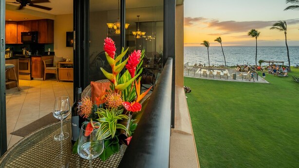 Ein Balkon mit Blick auf das Meer und eine Rasenfläche mit Personen.