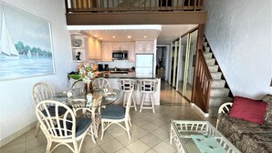 Un vaste espace de vie comprenant une table à manger, des chaises, un canapé et un escalier menant à l’étage supérieur.