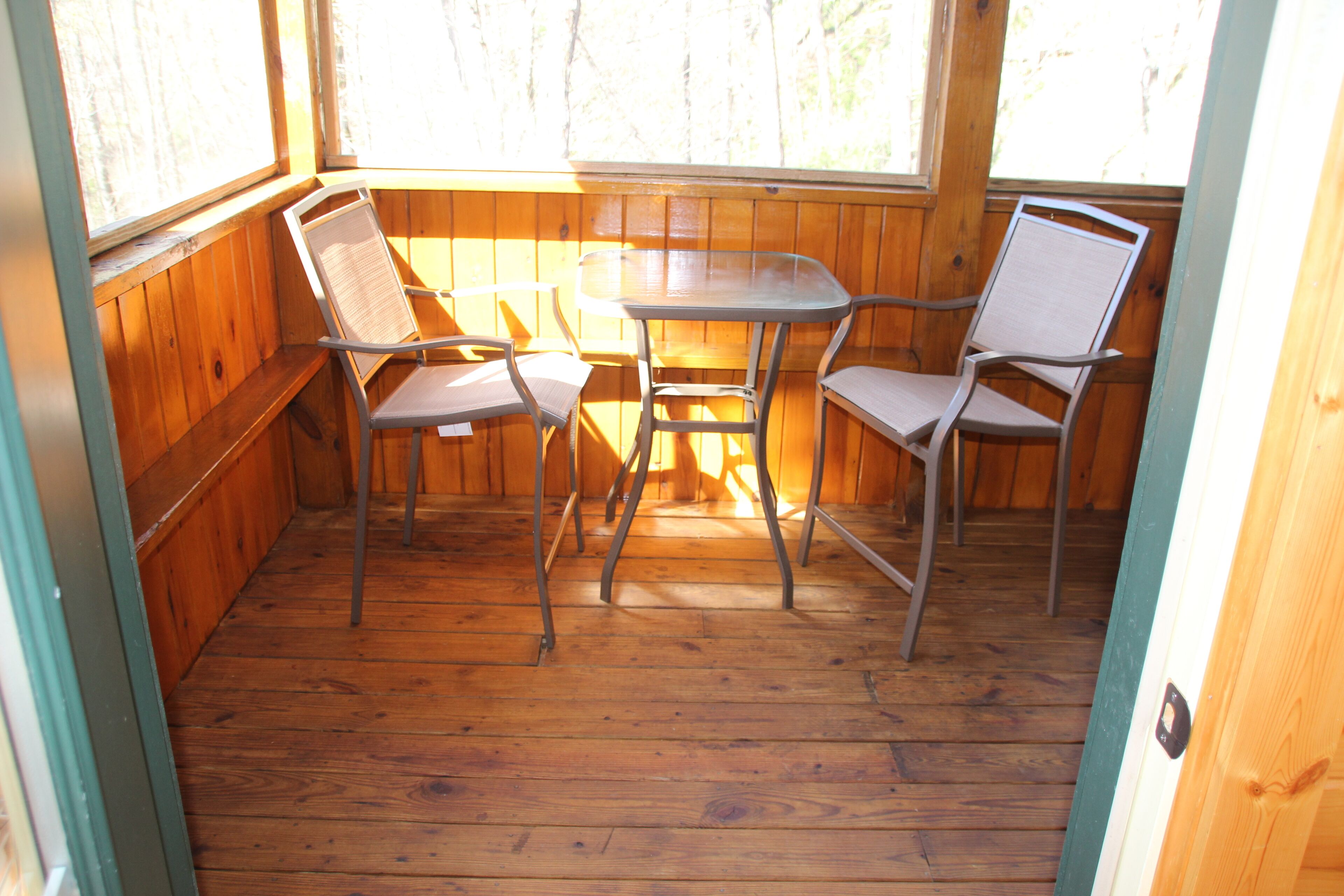 Una terraza de madera con una mesa y cuatro sillas.