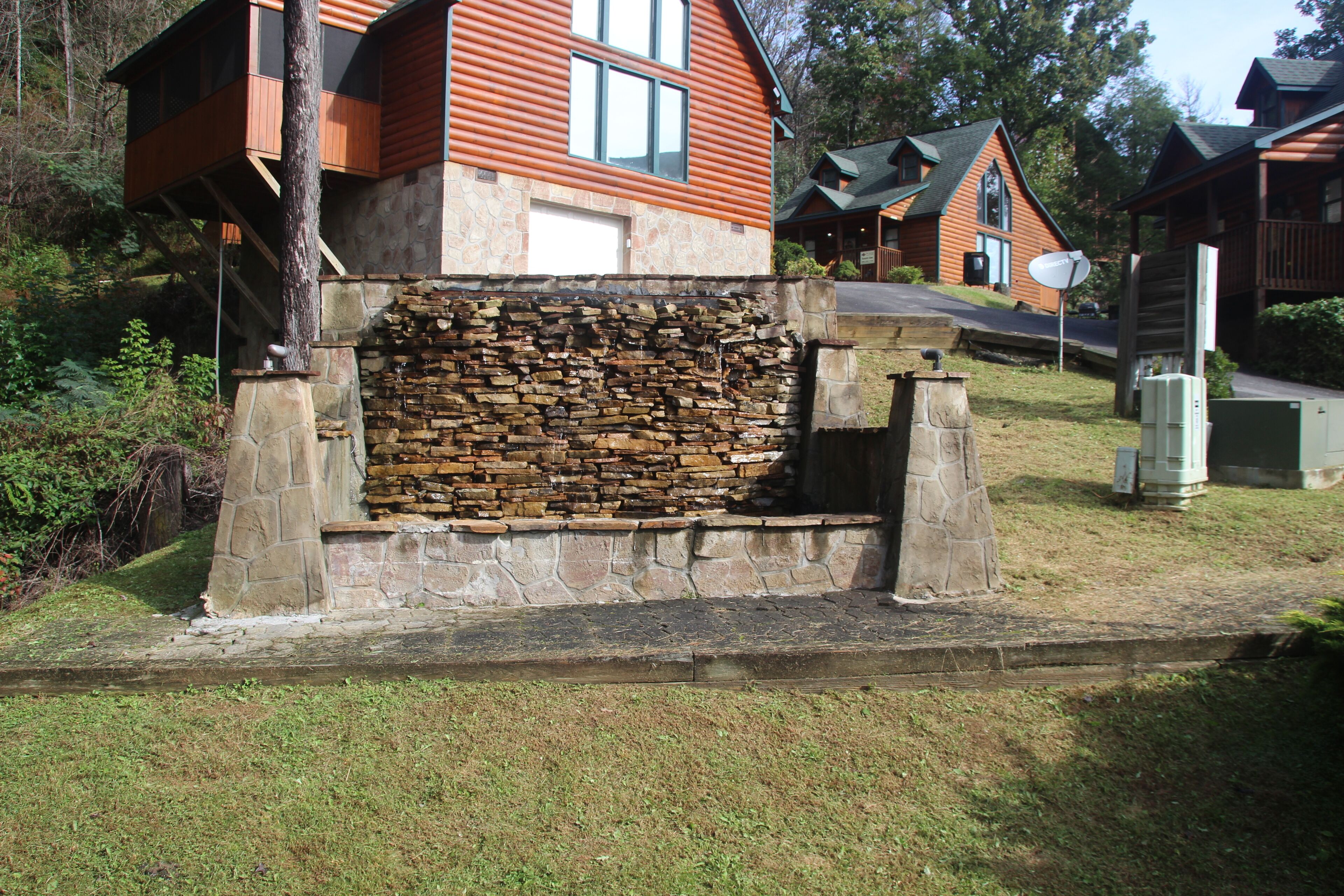 Una cabaña de troncos con un muro de piedra y una escalera de piedra que lleva a la entrada.