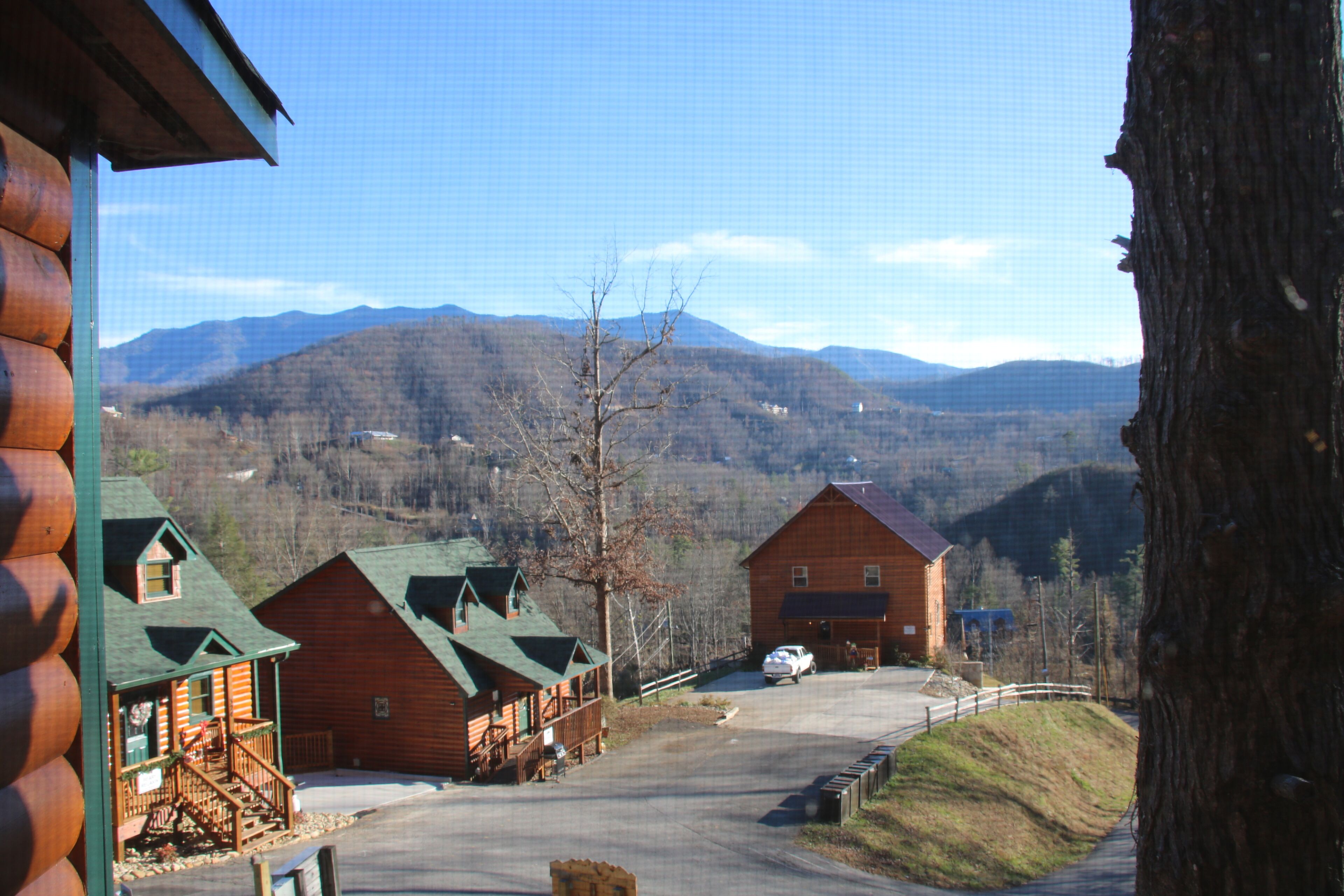 Un hôtel aménagé dans un chalet en rondins, composé de plusieurs bâtiments, avec une allée pavée et un paysage montagneux en toile de fond.
