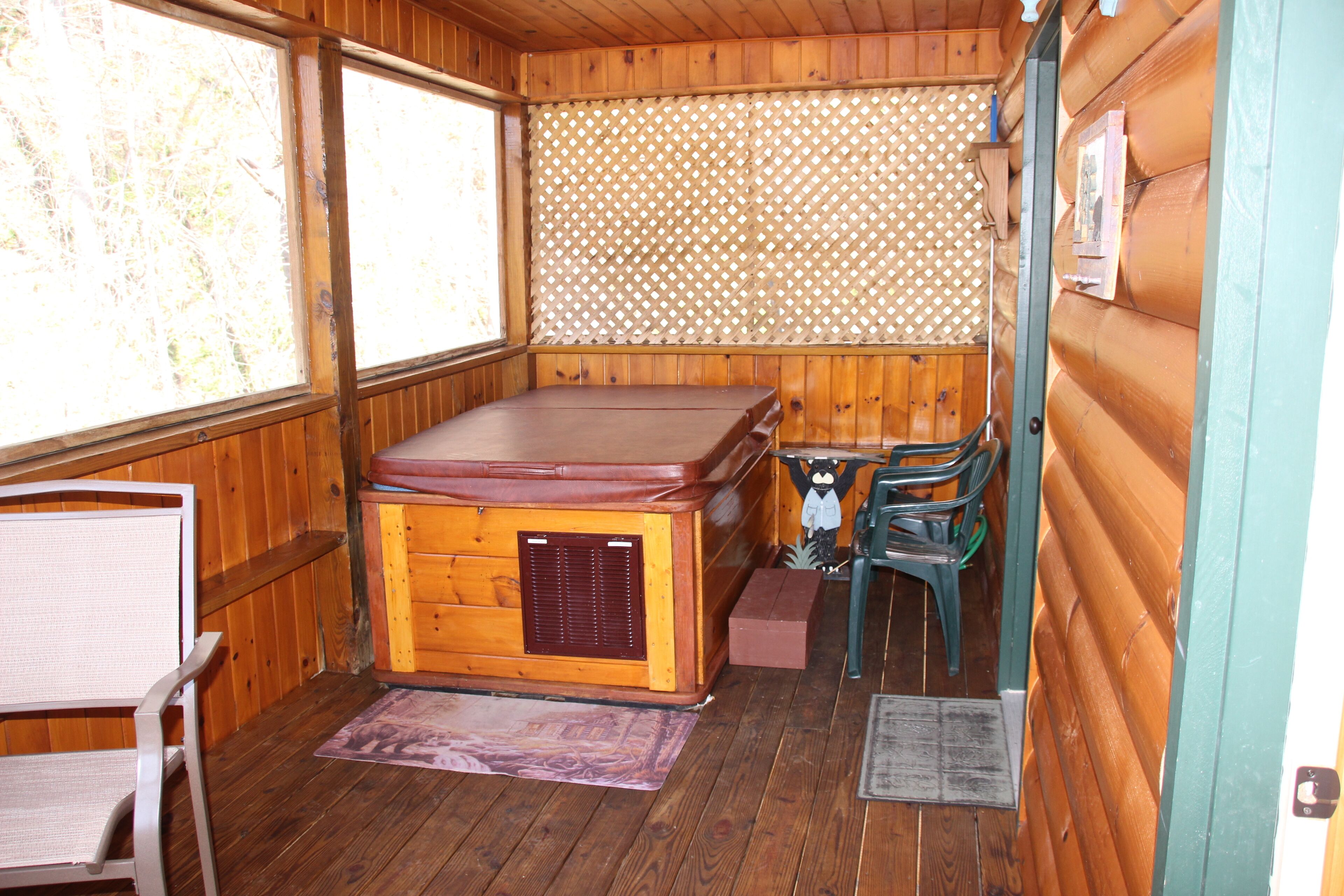 A wooden cabin with a hot tub, a chair, and a small table.