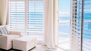 A spacious living room with a large window and a view of the ocean. - Guests Rate Us Exceptional: Beach chairs  & umbrellas available for rent. (Pensacola Beach)