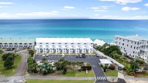 Un hôtel situé en bord de mer, composé de plusieurs bâtiments blancs, doté d’un parking et offrant une vue sur l’océan.
