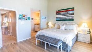 Une chambre à coucher avec un lit, un banc, des tables de chevet et un mur décoré de tableaux.