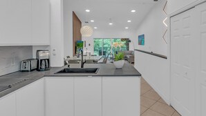 Una cucina moderna con isola integrata, una macchina da caffè e un'area pranzo con vista sul verde.