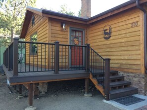 A wooden cabin with a wooden deck, a staircase, and a mailbox. - Charming Cabin In The Pines   (Estes Park)
