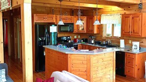 A spacious kitchen with wooden cabinets, a large island, stainless steel appliances, and pendant lighting.
