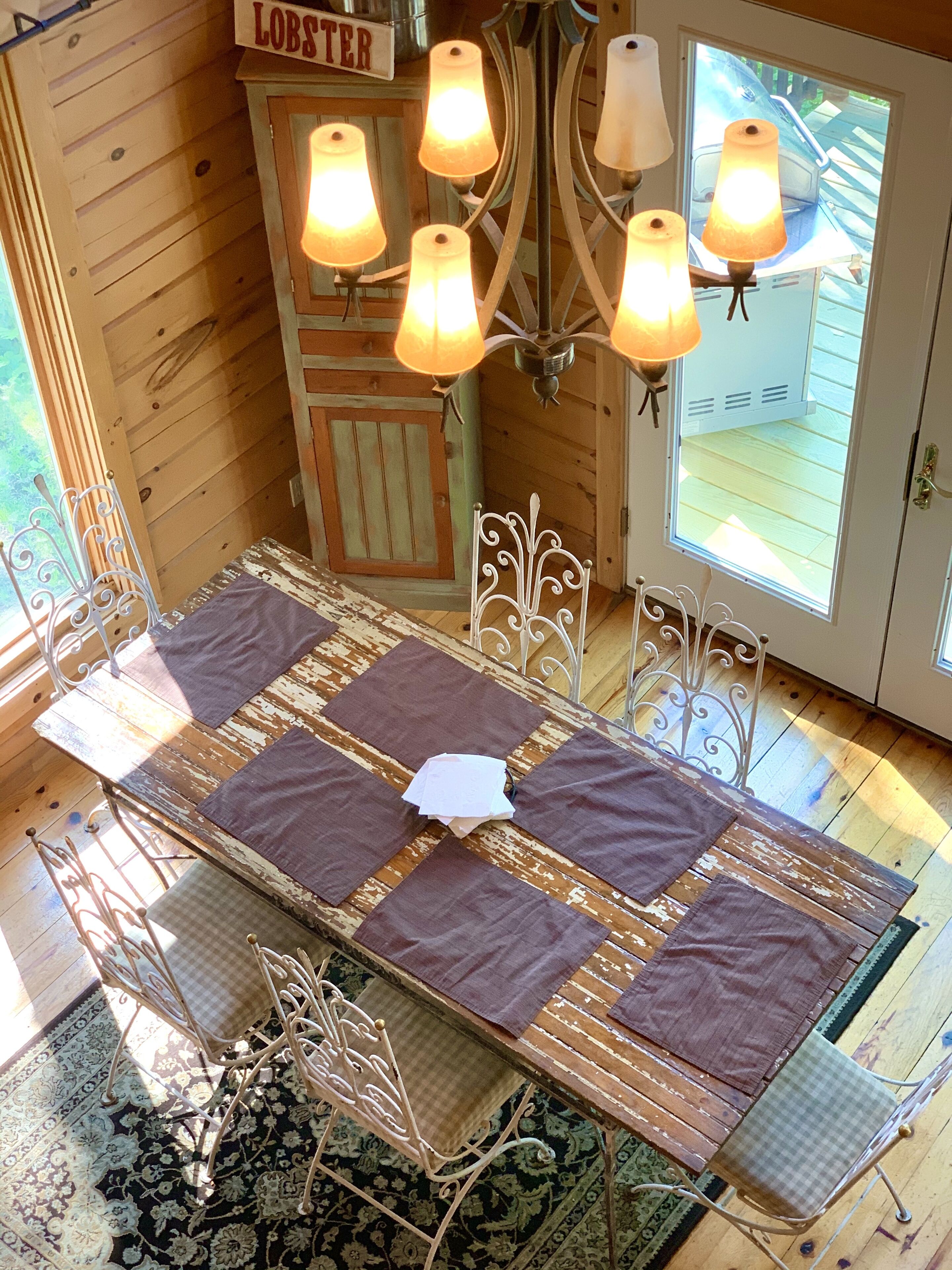 Un intérieur en bois comprenant une table à manger, des chaises et un lustre.