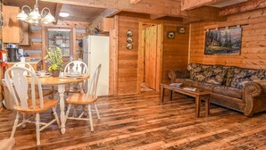 Ein Holzblockhaus-Interieur mit Essbereich, einer Couch und einem Bild an der Wand.