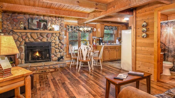 Ein gemütliches Blockhaus-Interieur mit Kamin aus Stein, Holzmöbeln und einer Küchenzeile.