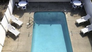 A rectangular swimming pool with a small hot tub, surrounded by white lounge chairs and a table with chairs. - Relax Oceanfront at our 2-bedroom Oceanfront condo in Carolina Beach (Carolina Beach)